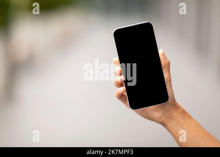 Hand holding modern smartphone with black empty screen, mockup Stock Photo