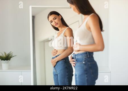 Woman Touching Belly Enjoying First Months Of Pregnancy At Home Stock Photo
