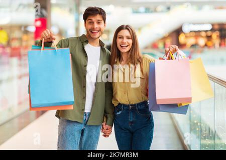 Happy Spouses Holding Paper Shopper Bags Shopping Posing In Hypermarket Stock Photo