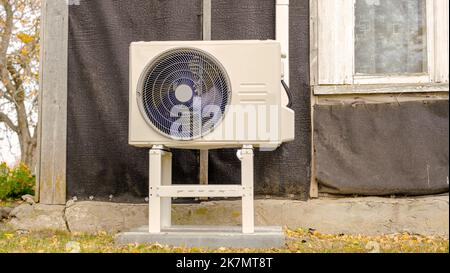 An air-to-air heat pump is installed on the exterior facade of the old house. Stock Photo