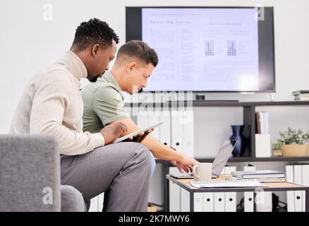 Sitting down to talk strategy. two businessmen using a laptop and digital tablet together in an office. Stock Photo
