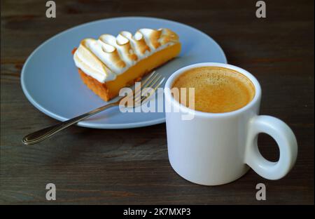 Closeup a Cup of Coffee with Blurry Lemon Meringue Tart in the Backdrop Stock Photo