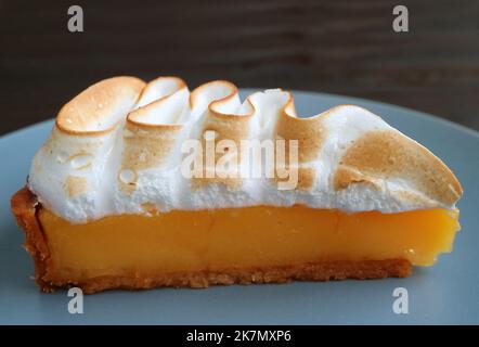 Closeup a Slice of Delectable Lemon Meringue Tart on a Blue Plate Stock Photo