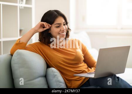 Smiling Young Arab Woman Relaxing With Laptop On Couch At Home Stock Photo