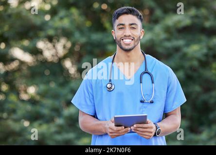 My tablet is what keeps me organised. a young male doctor using a digital tablet in nature. Stock Photo