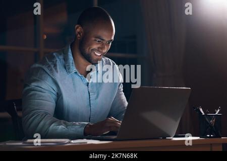 Burning the midnight oil. a young businessman using his laptop while working late at night. Stock Photo