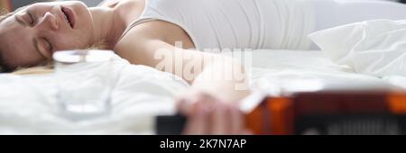 Drunk woman sleeps alone on a bed with a bottle Stock Photo