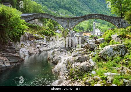 Old stone bridge and a church in the picturesque Lavertezzo village, Ticino, Switzerland. Lavertezzo is a popular travel destination in Verzasca valle Stock Photo