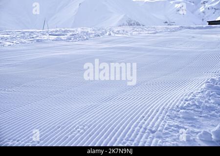 Snow lines after snowtrack at ski resort. Fresh ready ski slope looks like velvet snow. Groomed ski slope. Stock Photo