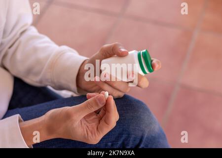 Close up top view of unrecognizable man hands holding a medicine bottle and pill in hands for medical purpouses Stock Photo