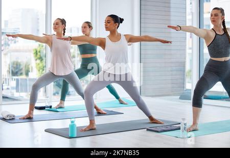 Discover your inner warrior. Full length shot of a diverse group of women practising yoga in the studio and holding a warrior pose. Stock Photo