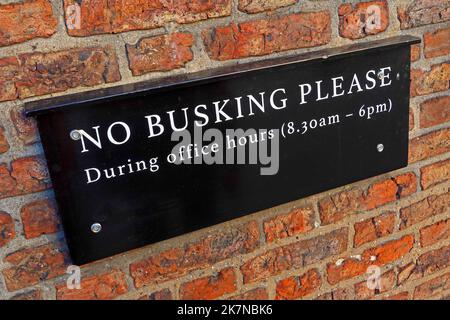 Very polite 'No busking please', during working hours (8:30am - 6pm) sign in Great Britain Stock Photo