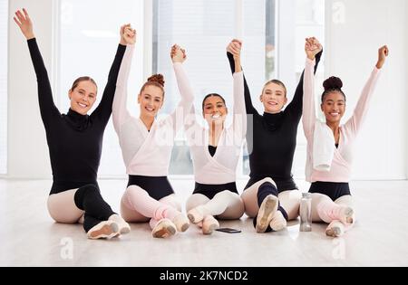 Cheering for our success. a group of ballet dancers with their arms raised. Stock Photo