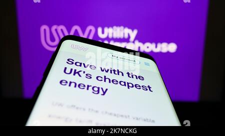 Mobile phone with website of British company Utility Warehouse (UW) on screen in front of business logo. Focus on top-left of phone display. Stock Photo