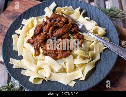 Brown stew chicken with tagliatelle on a plate. Italian cuisine Stock Photo