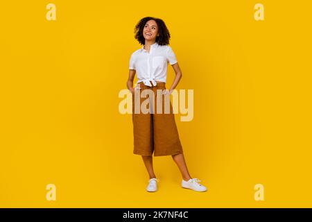 Full size photo of pretty mischief minded lady wavy hairdo has plan idea decide look blank space isolated on yellow color background Stock Photo