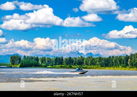 Tourists ride a motorboat; confluence of Talkeetna River; Susitna River & Chulitna River & Alaska Range; including Mount Denali beyond; Talkeetna; AK Stock Photo