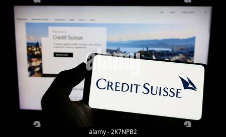 Person holding cellphone with logo of financial company Credit Suisse Group AG on screen in front of business webpage. Focus on phone display. Stock Photo