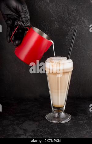 close-up of a barista preparing coffee with syrup and cream foam in a shop or cafe for a dessert of souffle cakes Stock Photo