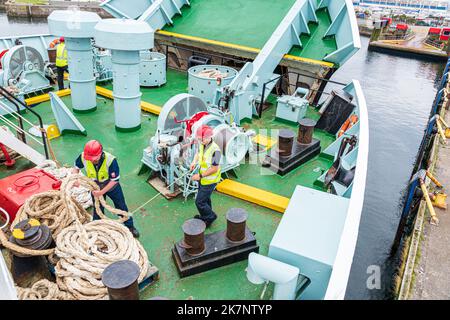Deck hands coiling mooring ropes on the CalMac ferry Isle of Arran leaving Ardrossan, North Ayrshire, Scotland UK to cross to Campbeltown Stock Photo