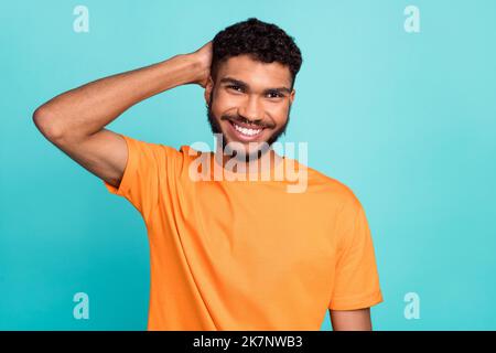 Photo of attractive cheerful guy wear orange t-shirt smiling arm head isolated teal color background Stock Photo