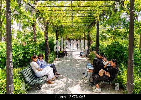 People sitting on benches in the Giardini Reali / Royal Gardens in Venice, Italy Stock Photo