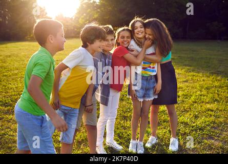 Friendly funny teen boys and girls in summer park have good time outdoors together with peers Stock Photo