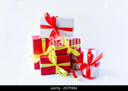 Red and gray gift box with yellow and red bows on a light background with silver confetti stars, a gift for holidays, Christmas, birthday Stock Photo