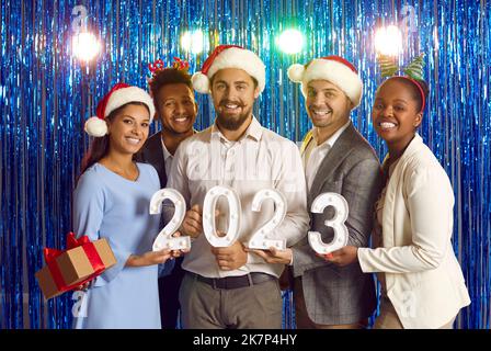 Portrait of happy joyful diverse corporate team with 2023 digits at New Year party Stock Photo