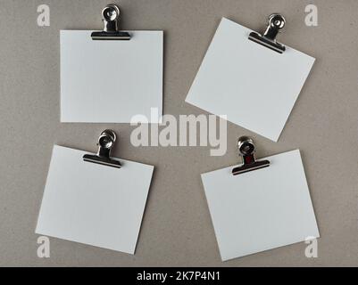 white blank paper notes with metal clips, isolated on gray textured board surface, note or messages template, taken straight from above Stock Photo