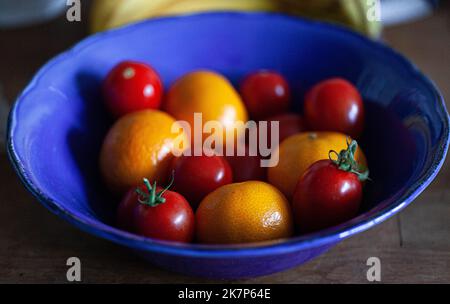 Cherry tomatoes and mandarins in a blue bowl. Stock Photo