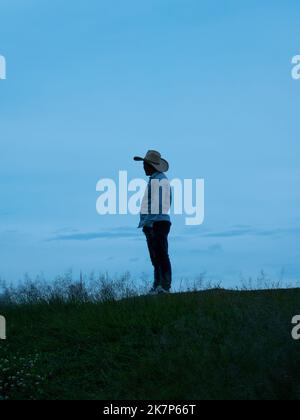 Jericó, Antioquia, Colombia - April 3 2022: A Colombian Man in a Hat and Shirt Stands on a Lookout Point Watching the Sky at Sunset Stock Photo