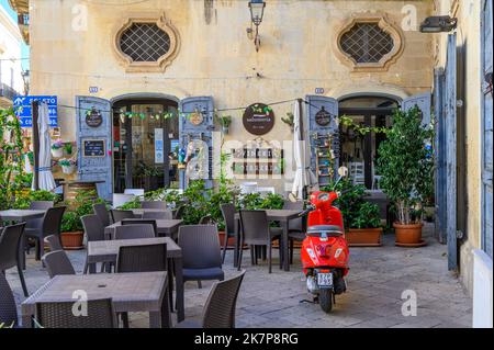 Outdoor seating and red moped in front of restaurant Salumeria Di Turno in Galatina old town, Apulia (Puglia), Italy. Stock Photo