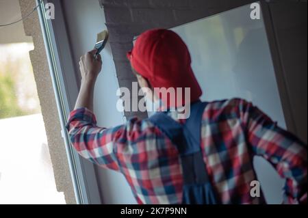 Experienced painter engaged in indoor wall painting Stock Photo