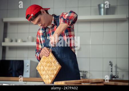 Focused young woodworker making a straw box Stock Photo