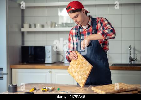 Concentrated carpenter making a straw box on the kitchen table Stock Photo