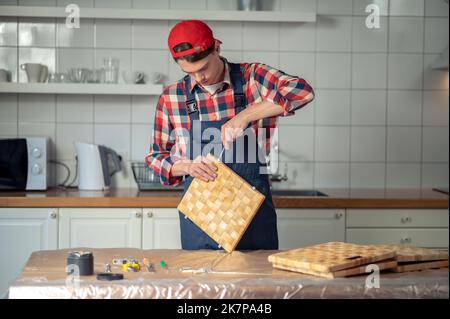 Serious focused woodworker making a straw box Stock Photo