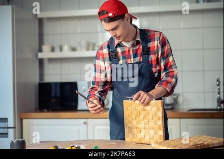 Serious focused carpenter looking at the tool in his hand Stock Photo