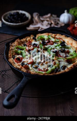 Large deluxe deep dish pan pizza against a dark background. Stock Photo