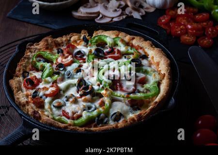 Large deluxe deep dish pan pizza against a dark background. Stock Photo