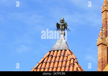 A decorative element of the top of the clay tile roof of Malbork Castle in the shape of an owl, blue sky backgrouns Stock Photo