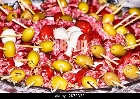 appetizers on skewers with olives. Buffet with canapes and appetizers on wooden skewers. Servelat sausage, olives, mozzarella cheese served on the buf Stock Photo
