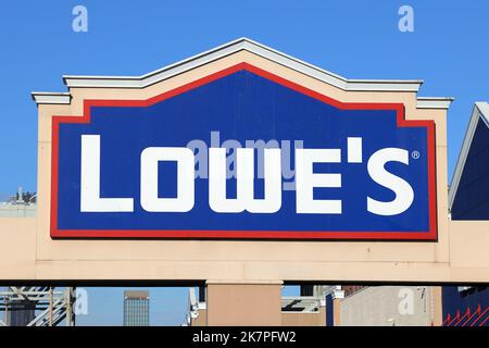 Logo and signage for Lowe's home improvement center set against a sunny blue sky. Stock Photo