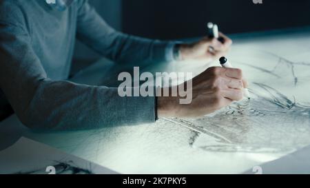 Closeup hands of a senior automotive graphic designer works with digital display graphics touch sreen table using a pen in a high tech innovative laboratory. Draws sketch of the prototype model of a car. Stock Photo