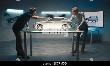 Experienced car designers and developers discuss the design and shape of the prototype model car made of clay in a hightech car manufacturing company. Stock Photo