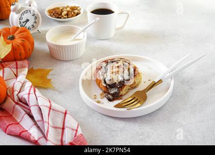 Homemade Pumpkin cinnamon rolls with cream cheese on the plate. Seasonal autumn homemade pastry - cinnabons for breakfast or holidays. Stock Photo