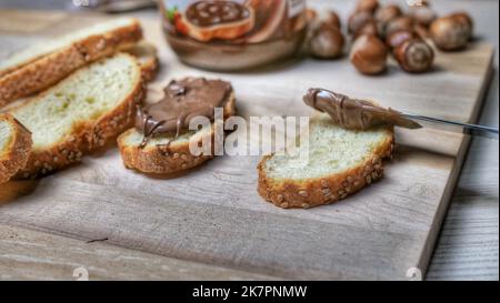 spreading chocolate-nut cream on bread with sesame seeds Stock Photo