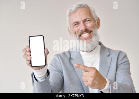 Older business man pointing at phone with white mock up screen isolated. Stock Photo