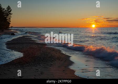 The sun sets into Lake Superior at the mouth of the Hurricane River in Pictured Rocks National Lakeshore in Alger County, Michigan Stock Photo