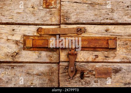Old vintage rusty iron latch on cracking door ,the door is made  of horizontal wooden boards Stock Photo